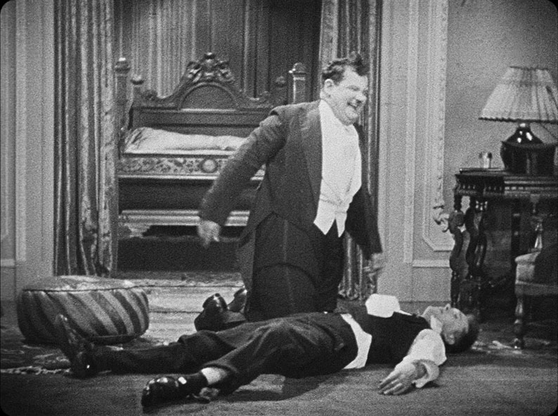 A drunken Ollie wrestles Stan to the ground in Early to bed