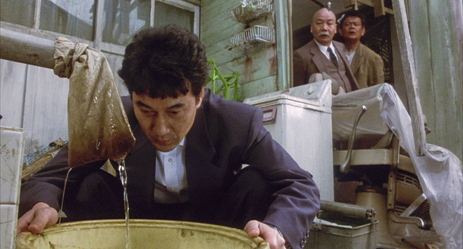 Takuro converses with his eel as Nakajimi and Takada watch curiously on
