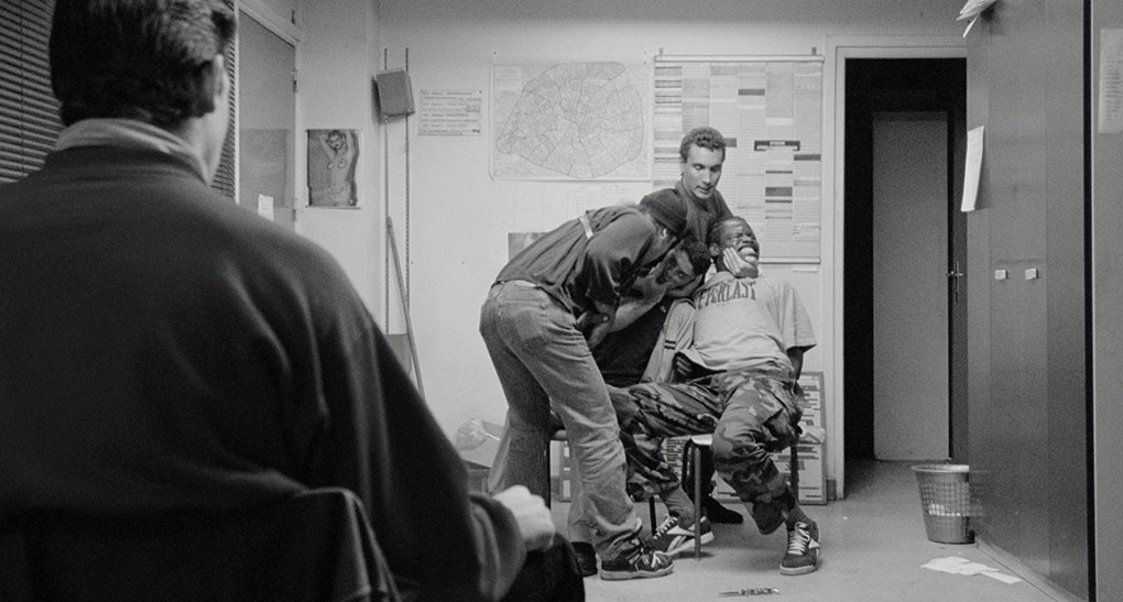 Two cops tirture Saïd and Hubert as their unhappy junior colleagues watches silently on