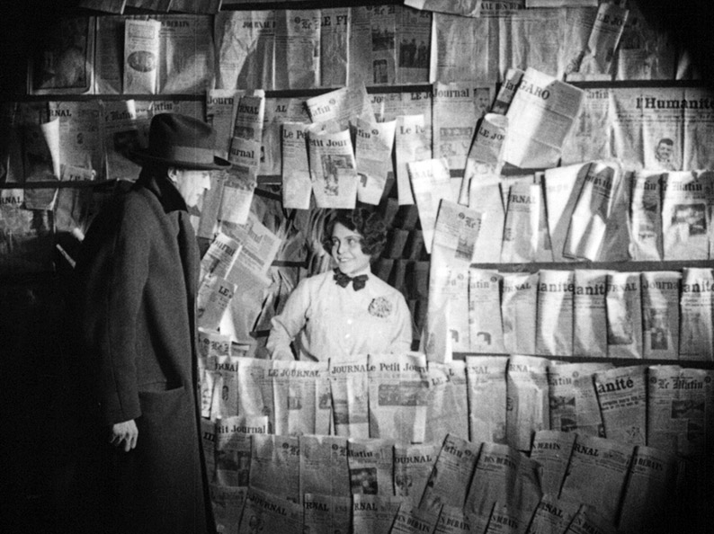 In one of the film's most striking compositions, Paul buys a newspaper froma news stand.