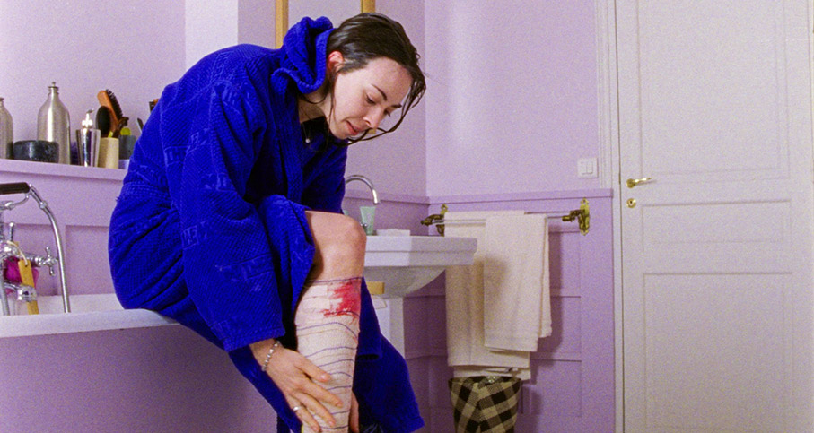 Esther examines her leg in Sandrine's bathroom